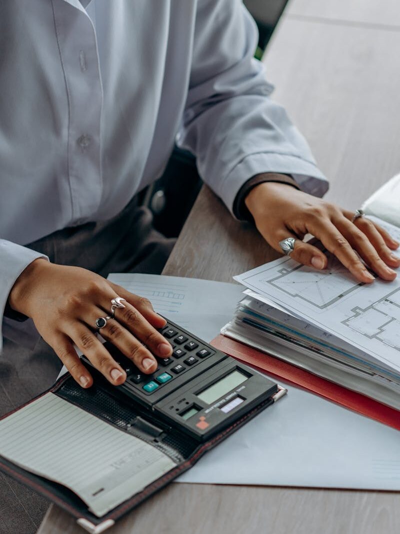 pexels-photo-8297220-8297220 Accountant calculates finances with a calculator and documents on a desk.